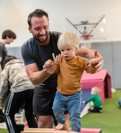 kid on balance beam with happy instructor