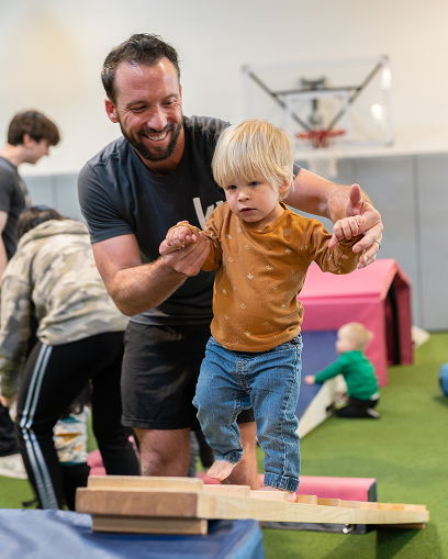 kid on balance beam with happy instructor